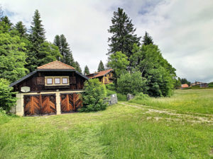 Une maison en bois au milieu d'un champ herbeux.