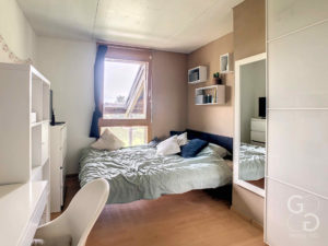 Une petite chambre avec un lit et un bureau.