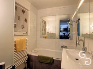 Une salle de bain avec baignoire, lavabo et miroir.