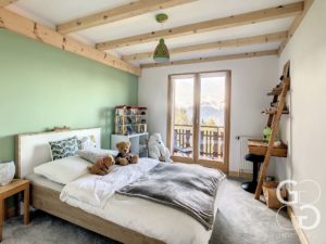 Une chambre verte avec poutres en bois et ours en peluche.