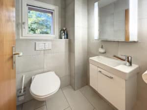 Une salle de bain avec WC, lavabo et fenêtre.