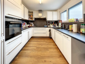 Une cuisine avec un plancher en bois et des armoires blanches.