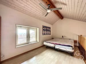 Une chambre avec un lit et un ventilateur de plafond.