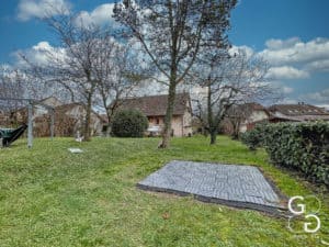 Un terrain en herbe avec des arbres et une maison en arrière-plan.