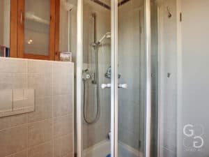 Une salle de bain avec cabine de douche vitrée et toilettes.
