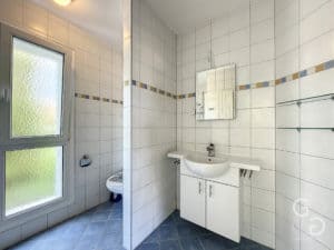 Une salle de bain avec murs carrelés et lavabo.