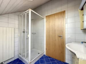 Une salle de bain carrelée bleue avec cabine de douche et lavabo.