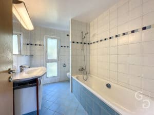 Une salle de bain carrelée bleue avec baignoire et lavabo.