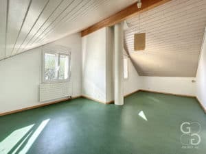 Une pièce avec un sol vert et un plafond en bois.