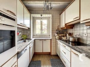 Une petite cuisine avec des armoires blanches et une cuisinière.