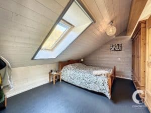 Une chambre avec un grenier et un lit.