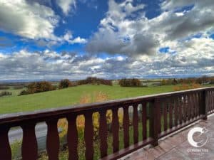 Une vue depuis un balcon donnant sur un champ et des nuages.