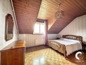 Une chambre avec parquet et lit en bois.