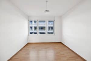 Une pièce vide avec des murs blancs et du parquet.