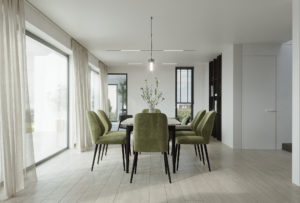 Une salle à manger moderne avec des chaises vertes et des murs blancs.