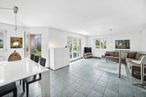 Salon lumineux et aéré avec mobilier moderne et accès à un jardin.