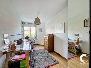 Un espace de bureau à domicile lumineux et organisé avec un bureau, une chaise, des tiroirs de rangement et un tapis décoratif.