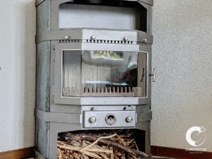 Poêle à bois moderne avec un compartiment de rangement pour le bois de chauffage en dessous.