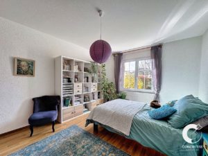 Chambre lumineuse et confortable avec un grand lit, une bibliothèque et des plantes décoratives.