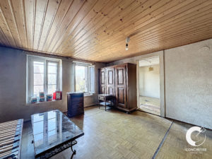 Une pièce vide avec des plafonds en bois, une table en verre et une armoire ancienne.