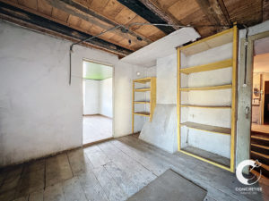 Une pièce vide avec un parquet et une porte jaune partiellement ouverte avec des étagères attachées.