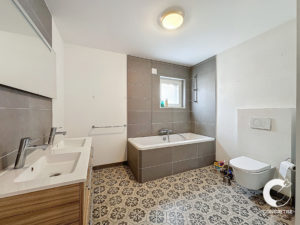 Intérieur de salle de bains moderne avec carrelage à motifs, baignoire, lavabo et toilettes.