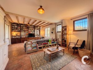 Cozy living room with a large wall of bookshelves, wooden beams, and a play area for children.