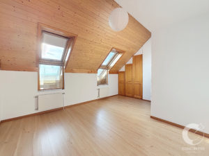 Attic room with a slanted pine ceiling, two skylights, light wood floor, built-in wooden wardrobe, white walls, and a hanging paper lantern.